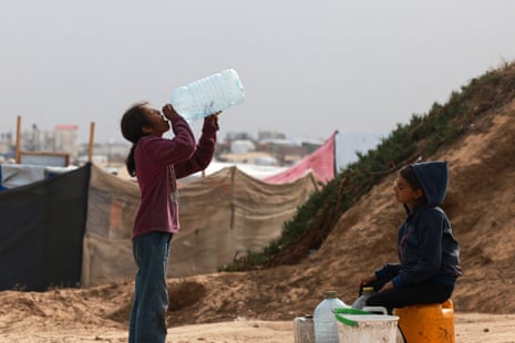 Displaced Palestinian children take a drink at the tent camp in Rafah, 26 April.