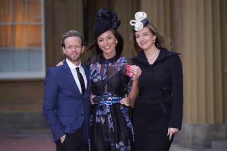 McCall holding up her MBE, alongside Michael Douglas and Holly Robertson