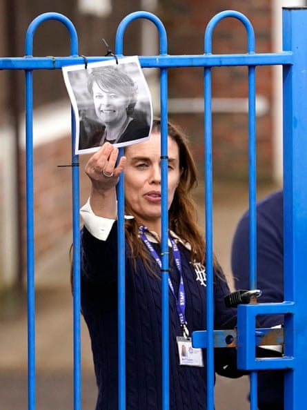 Headteacher Flora Cooper touches a photo of Ruth Perry through a schoolgate