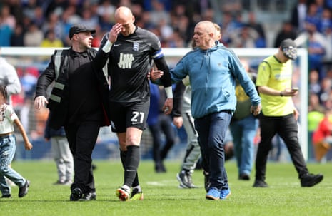 Birmingham City keeper John Ruddy looks dejected as he is escorted off the pitch as fans invade, after Birmingham City are relegated to League One.