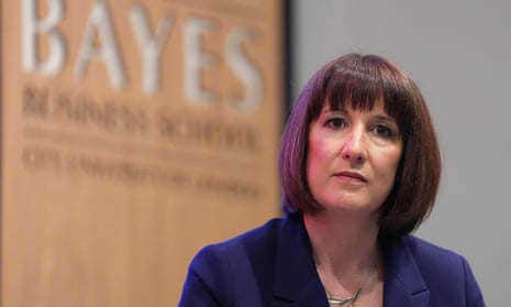 Rachel Reeves on a podium, with a large wooden sign displaying the logo of the Bayes business school behind her