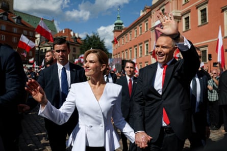 Karol Nawrocki and his wife Marta Nawrocka wave as they walk near the Royal Castle in Warsaw on the day he took the oath of office in August 2025.