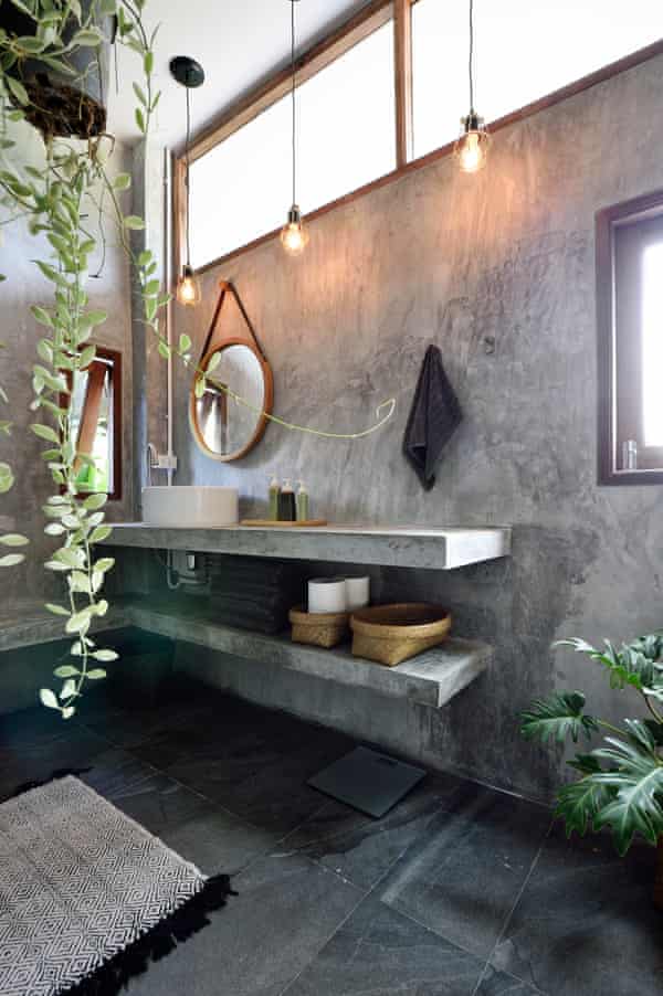 Vanity in a luxury concrete bathroom with candles, hanging plants and soaps