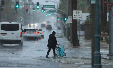 A person pushes a cart on a flooded street near Palm Springs.