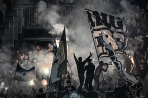 Fans wave huge flags and let off flares