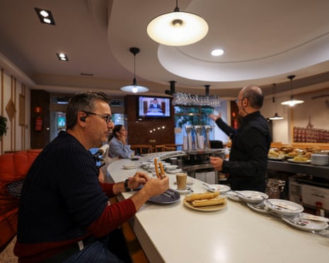 People sit at a bar as Spain's prime minister Pedro Sanchez is seen on a screen, calling an early election in Madrid, Spain.