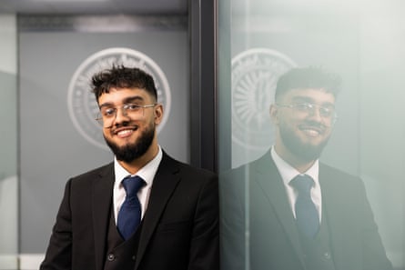 Raihaan Abbas smiling while leaning against a glass wall