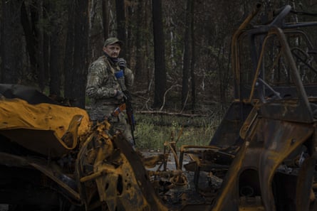 A Ukrainian serviceman walks along a road searching for dead bodies of his comrades