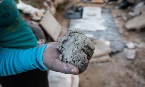 A woman employed as a rock crusher in the abandoned mining town of Durban Deep shows a handful of earth that will be processed to extract gold