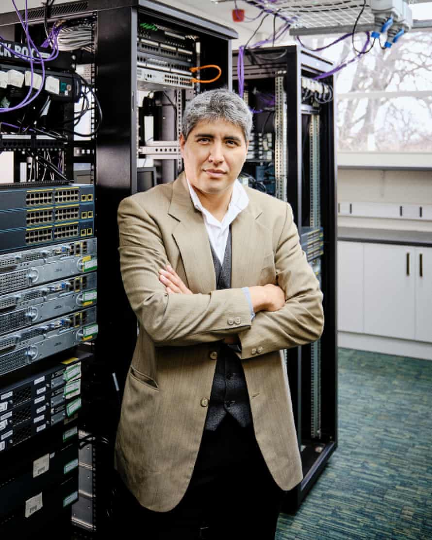 Christian Nunez Fuentes bir bilgisayar ekipmanı rafının önünde duruyor.