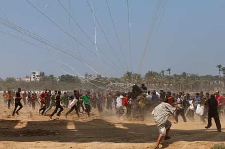 Palestinians run towards airdropped aid packages in Deir al-Balah, in the central Gaza Strip, on 18 August 2025.