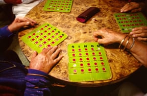 bingo cards on a wooden table with older peoples' hands reaching for them