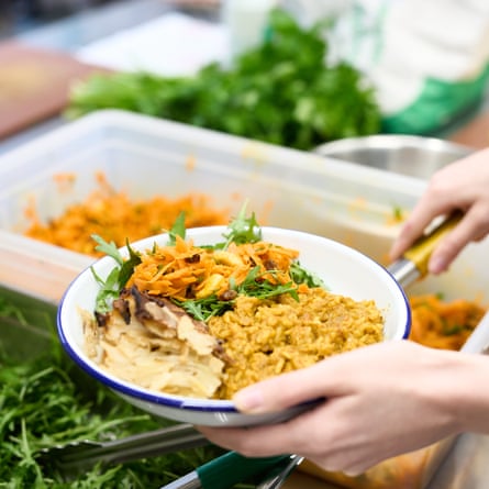 A person putting food on a plate including carrot salad