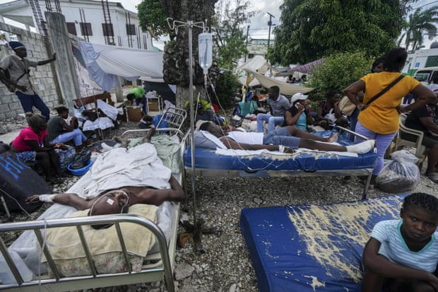 Injured people lie in beds outside the Immaculée Conception hospital in Les Cayes, Haiti
