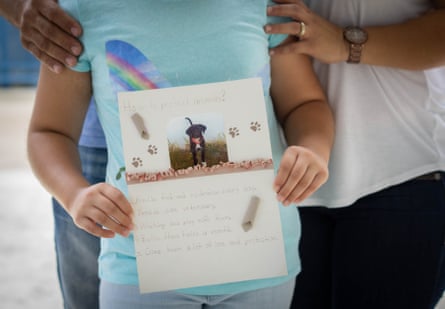 Alejandra, 9, with her parents, holds a photo of her dog Nisan used for a school project.