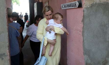 A young woman carries a baby as she walks past sign “Shelter” during airstrike alarm near Transfiguration Cathedral damaged as a result of a missile strike in Odesa the day before, prior service on 24 July 2023, amid the Russian invasion of Ukraine.