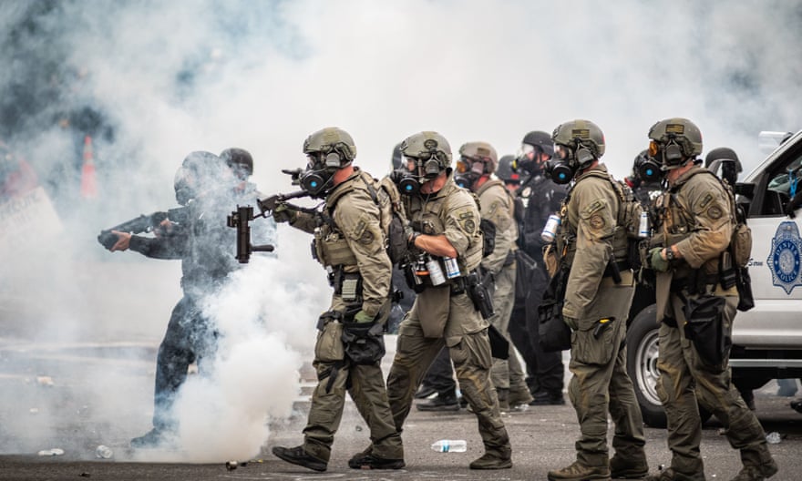 Riot police points weapons as they move through a cloud of teargas at a Black Lives Matter protest in Denver.