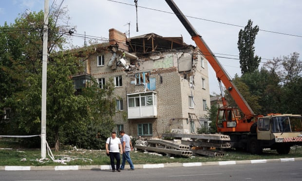 Municipal workers using a crane trying to make a building safe after a rocket strike.