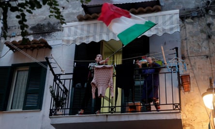 A woman waves an Italian’s flag on a balcony in Naples