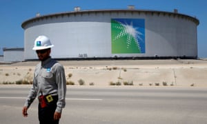 A Saudi Aramco employee walks near an oil tank at the Ras Tanura refinery and terminal in Saudi Arabia