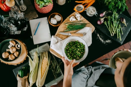 a person holding vegetables and developing a recipe with a notebook and pencil