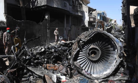 Security personnel stand beside the wreckage of a plane at the site after a Pakistan International Airlines aircraft crashed in a residential area in Karachi