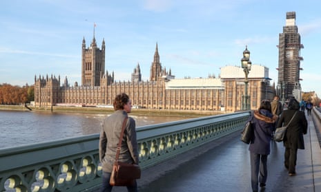 People walk across Westminster bridge next to the Houses of Parliament.