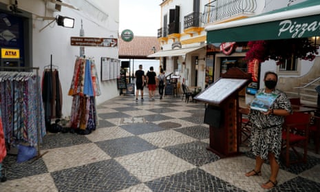 A server offers a menu on a quiet street during the coronavirus pandemic in downtown Albufeira, in the Algarve region of Portugal on Monday.