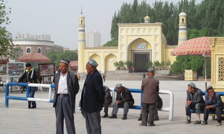 On Liberation Avenue, outside Kashgar’s Id Kah mosque, Uighur men watch security forces file past for the city’s latest mass “anti-terror” rally