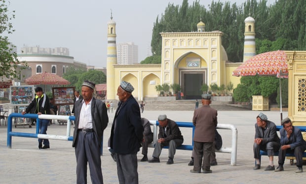 Uighur men watch China security forces file past during an “anti-terror” rally in Kashgar, Xinjiang.