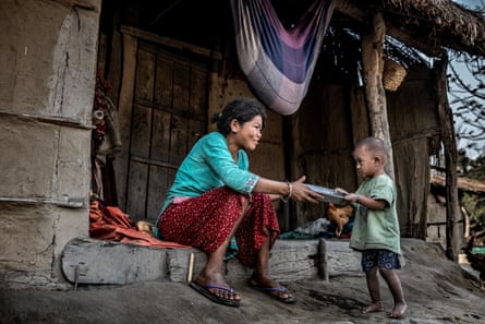 A woman and a child hold a plate between them on the step of a dwelling
