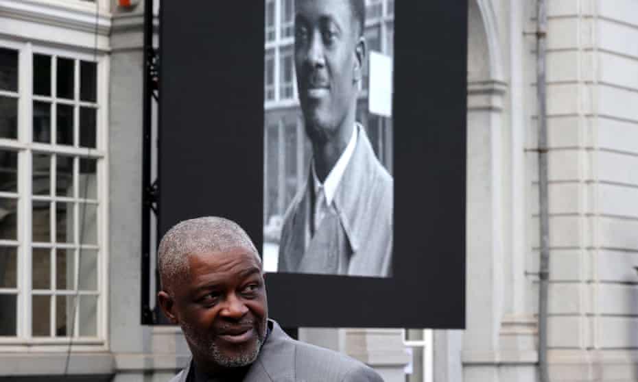Roland Lumumba, a son of Patrice Lumumba, walks by a banner bearing a photo of his late father, in Brussels.