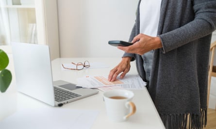 Mulher com contas financeiras usando uma calculadora e um laptop em uma mesa