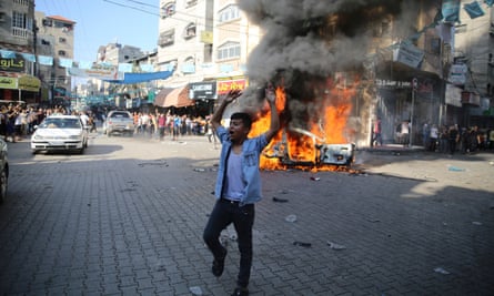 A Palestinian celebrates near a burning stolen Israeli civilian car in Beit Lahiya, Gaza, on Saturday.