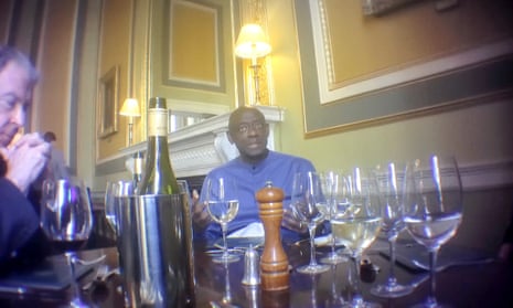 Johnston Busingye and Terence Fane-Saunders sitting in a fine dining room at a table with a bottle of wine and a number of wine glasses on it