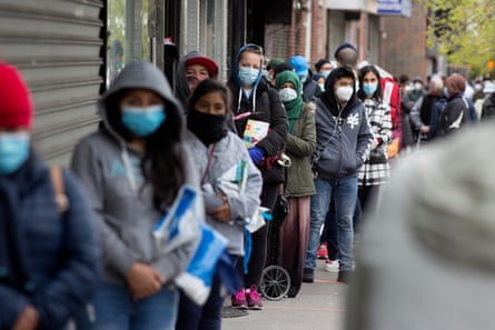 People wearing face masks wait in line to receive free food from a pantry in Brooklyn, New York, on 8 May.