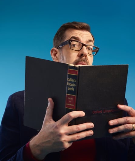 Richard Osman holding up a large encyclopedia