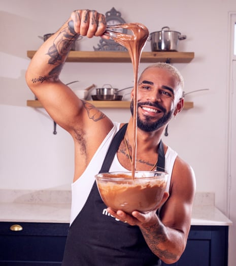 Sandro Farmhouse holding a glass bowl of melted chocolate in one hand and a whisk, high above it, with melted chocolate dripping from it into the bowl, with the other, and smiling