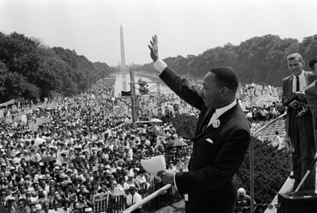 a man in a suit waves to a large crowd
