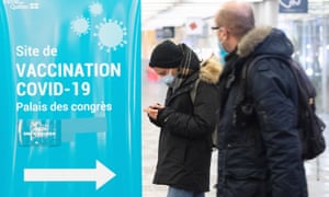 People walk by a Covid-19 vaccination sign at a vaccination site in Montreal, on 8 January.