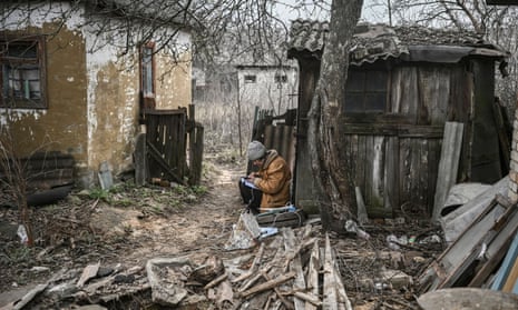 A woman keeps notes and uses her phone in a home yard in the town of Chasiv Yar, near Bakhmut
