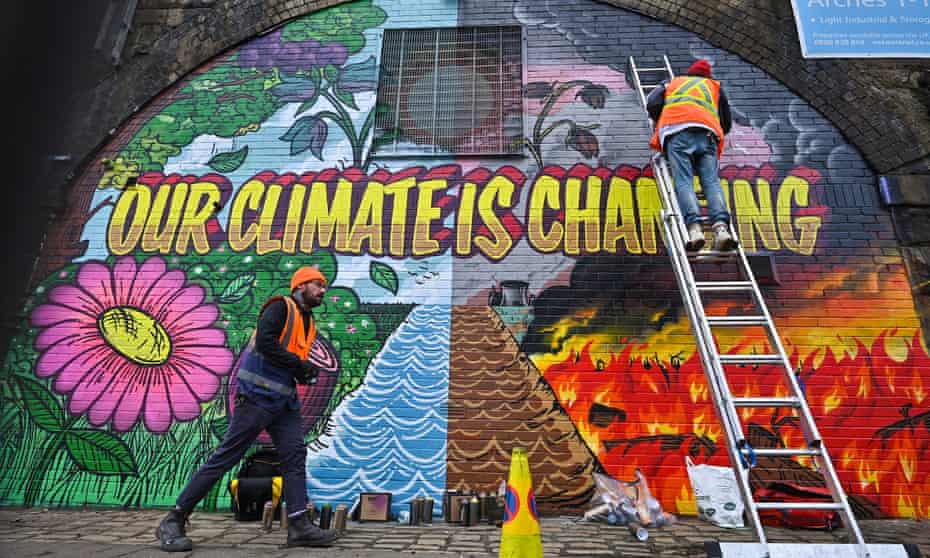 Artists paint a mural on a a wall next to the Clydeside Expressway near one of the Cop26 venues