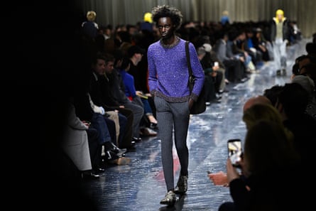 A model wears a purple sequin top, skinny grey trousers and snakeskin boots