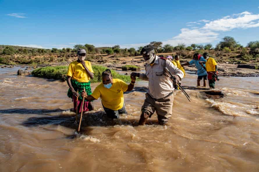 Health visitors wade across a river.