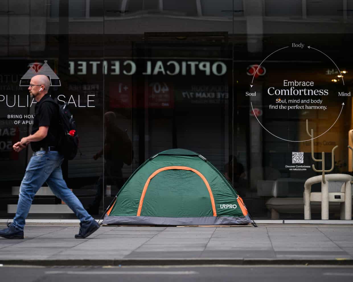 A man walks past a homeless person’s tent pitched on a London pavement