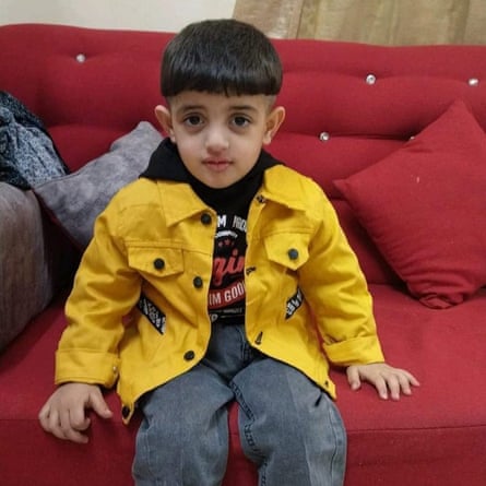 A small boy sitting on a red sofa.