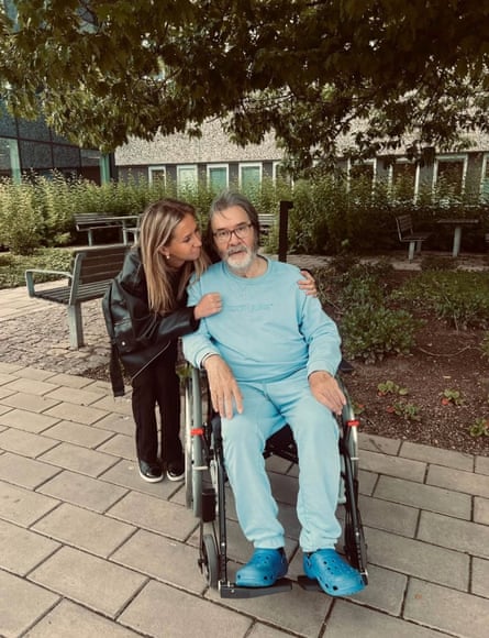George Mason in a wheelchair with Michelle putting her arms around his shoulders