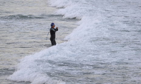 A lone swimmer enters the ocean at Coogee Beach in Sydney wearing a wetsuit and cap and goggles