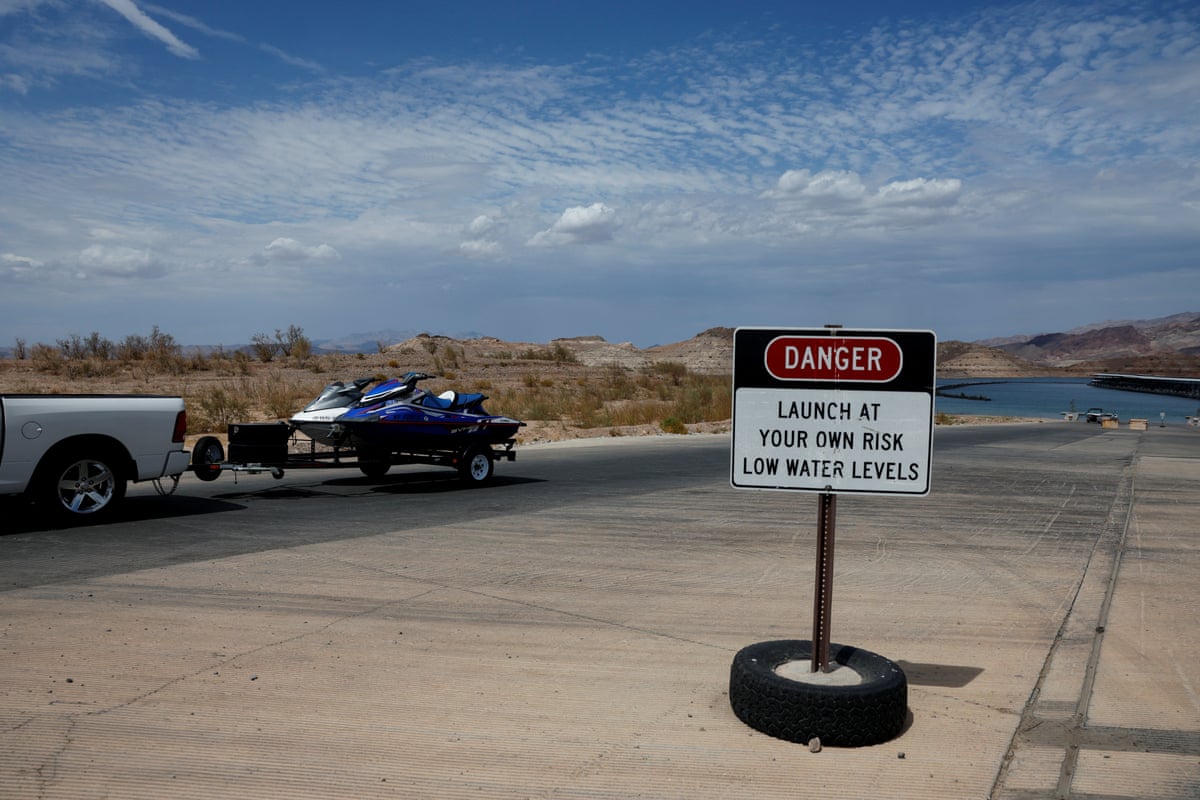 A vehicle towing a jet ski drives by a warning sign