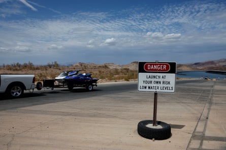 A vehicle towing a jet ski drives by a warning sign
